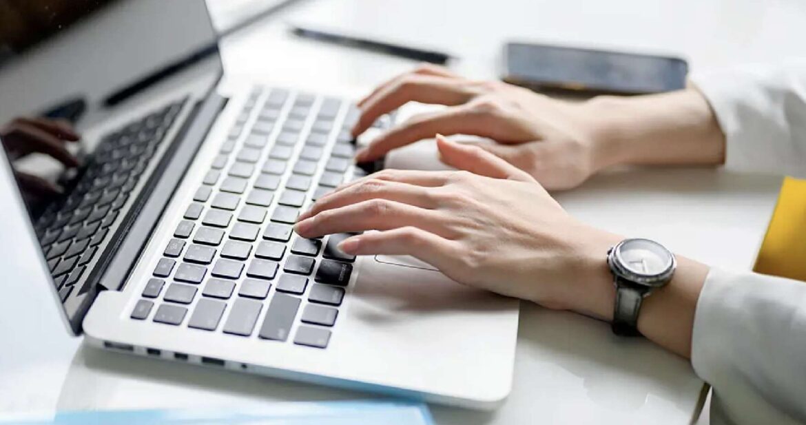 A woman's hands typing on the keyboard of a laptop computer