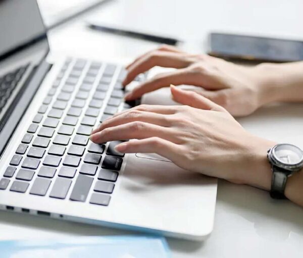 A woman's hands typing on the keyboard of a laptop computer