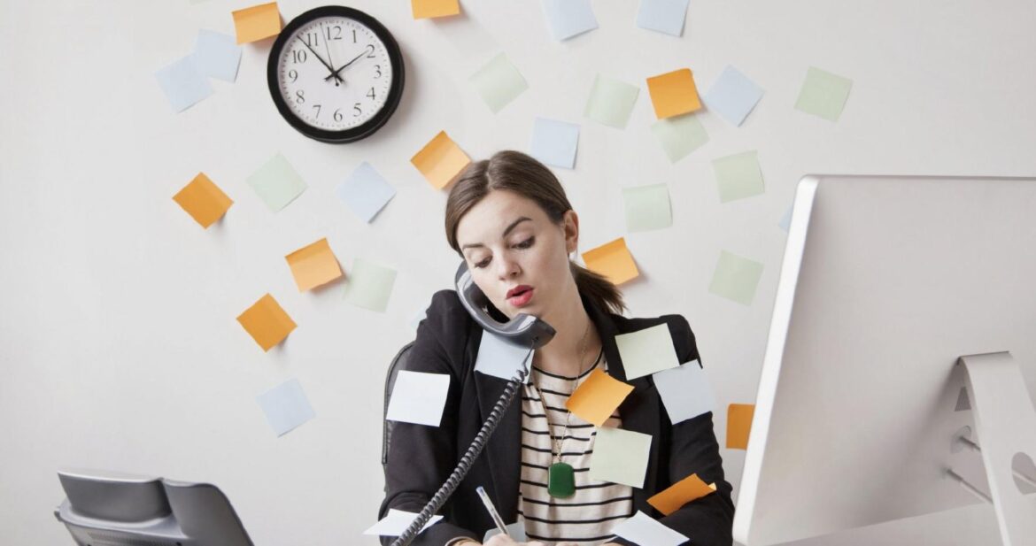 Image of a worried woman in the office with multiple tasks