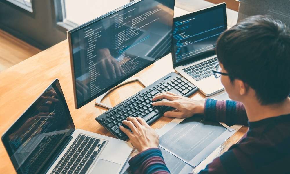 Person seated working on a computer with several screens at the same time