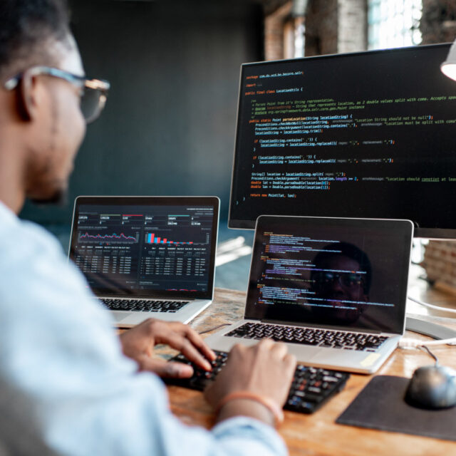 software_development Software developer working in code on three screens simultaneously